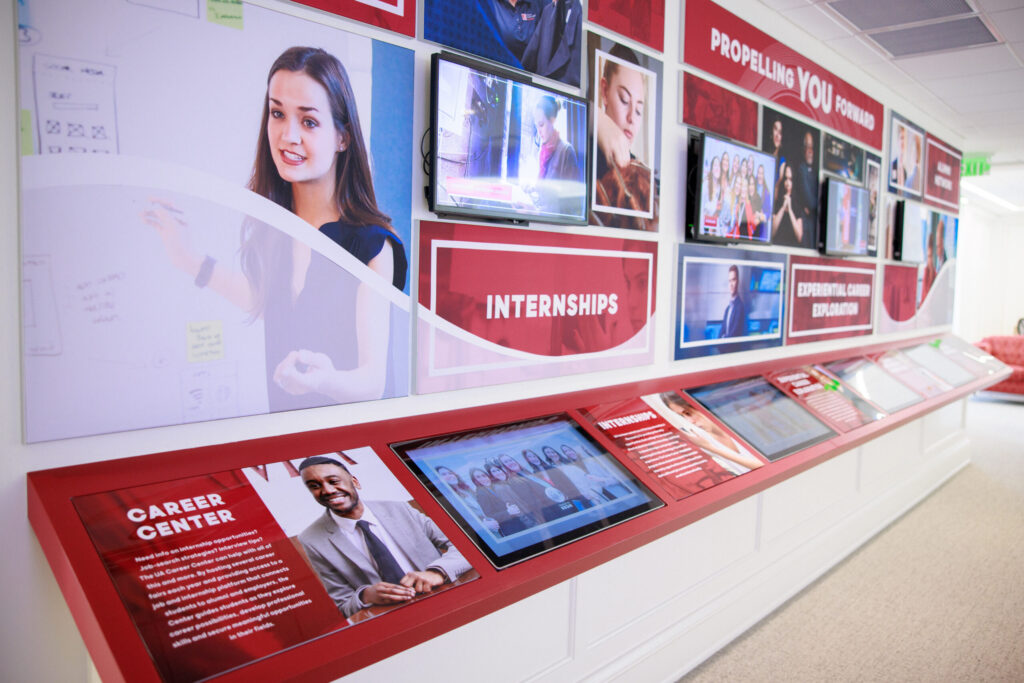 An interactive display wall at an academic center showing various multimedia elements about internships, career opportunities, and student engagement. The display is colorful and informative, intended to guide students in their career paths.