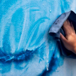 Person wiping graffiti off a surface protected by anti-graffiti film, showing easy removal and surface protection from vandalism.