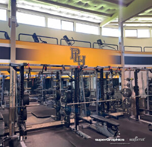 Pacific Lutheran University's Names Fitness Center, showcasing branding with soffit wall graphics in the weight room. School graphics enhance the space, reflecting the university's identity.