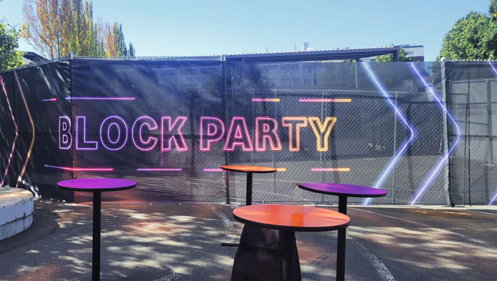 Bold and colorful block party signage on mesh, crafted for sustainable outdoor branding in Seattle.