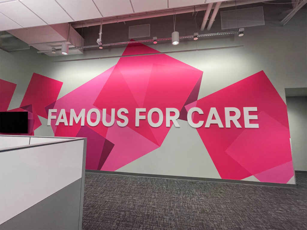 Corporate office wall graphic, produced and installed by SuperGraphics. Showcases T-Mobile's pink branding rotating cubes design with the message, "Famous for care."