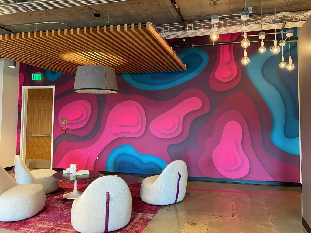 T-Mobile Corporate T-Mobile branded wall mural for corporate office, completed by SuperGraphics. Showcases magenta and blue topographic design in front of lounge area.