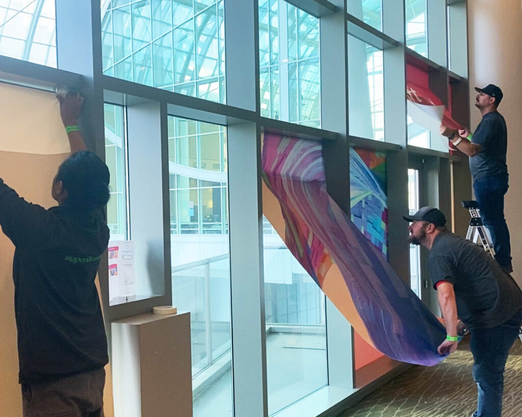 Graphic installation for Microsoft event, produced and installed by SuperGraphics. Showcases graphic installers installing Microsoft branded wall murals at corporate event.