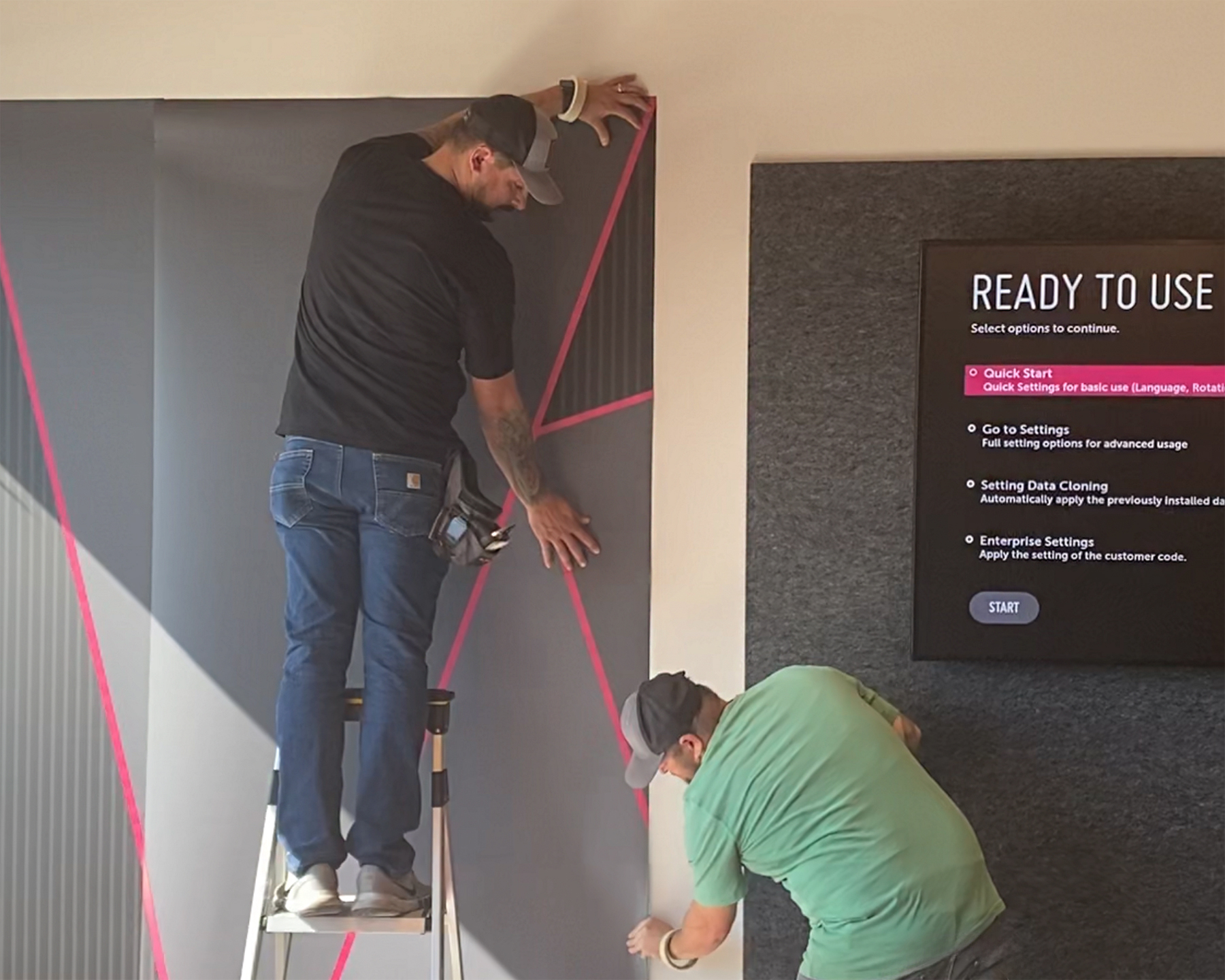 Graphic installation for T-Mobile Store, produced and installed by SuperGraphics. Showcases graphic installers installing pink and gray wall graphics in T-Mobile.