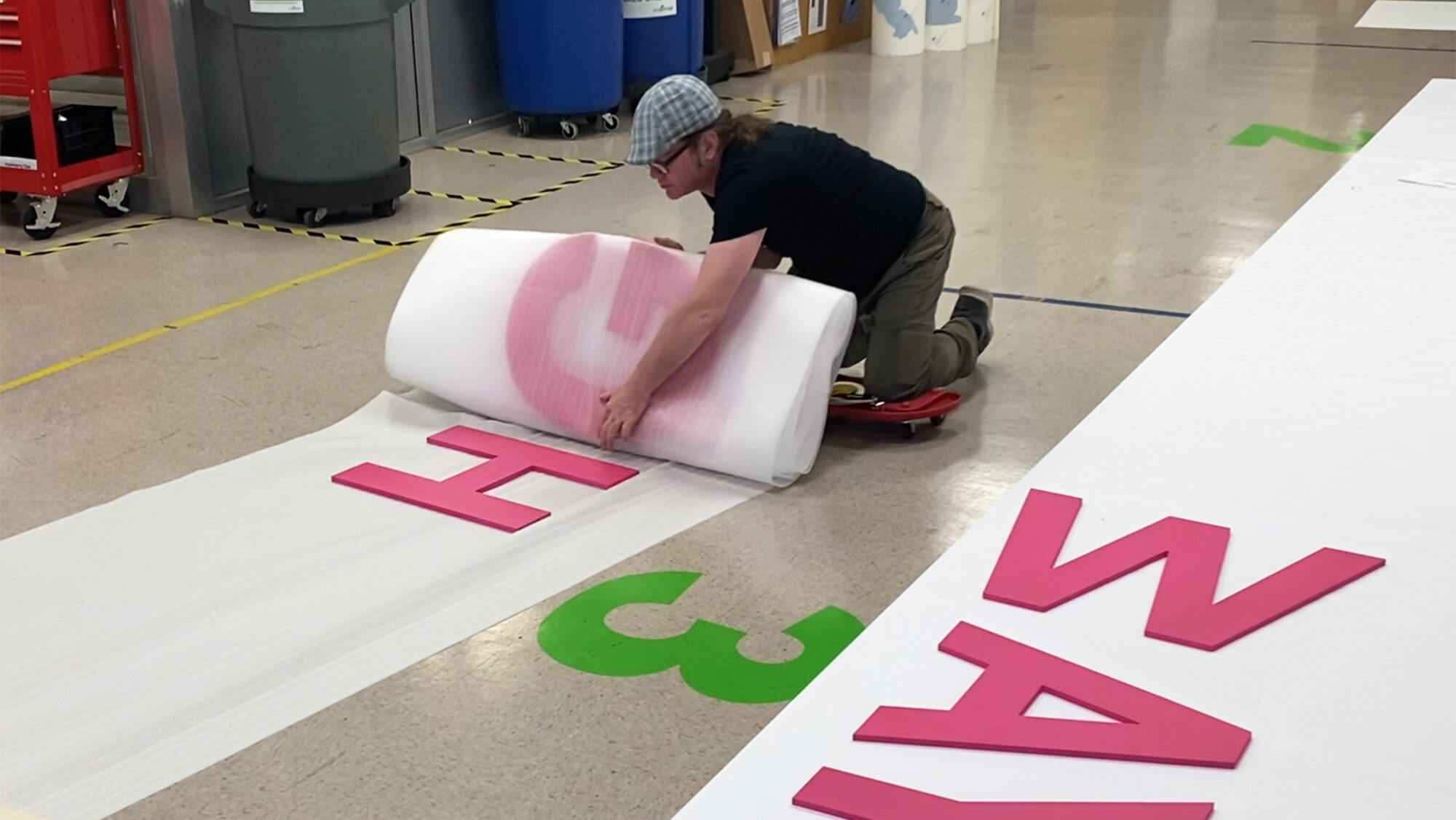 Retail campaign kitting example, produced by SuperGraphics. Showcases employee wrapping up dimensional lettering for shipping.