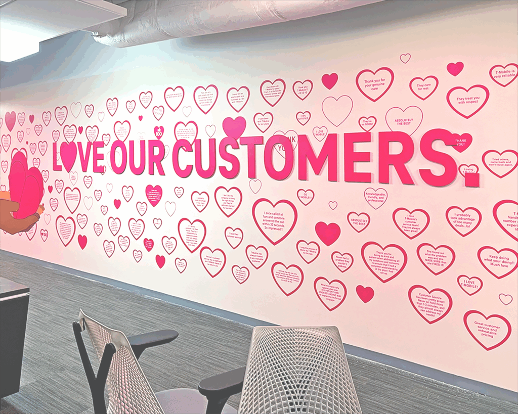 Dimensional lettering and custom vinyl wall graphic in an office hallway reading "LOVE OUR CUSTOMERS" surrounded by red and pink heart decals.