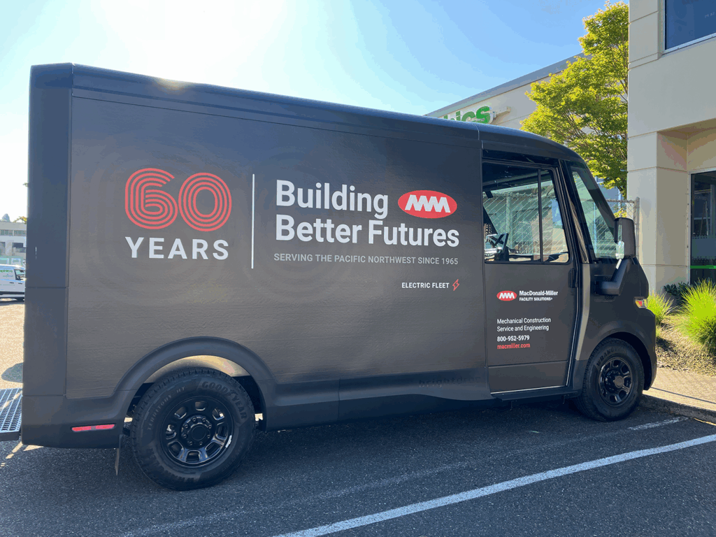 MacDonald-Miller electric fleet van wrap on a matte black finish celebrating '60 YEARS' with corporate branding and 'Building Better Futures' message.