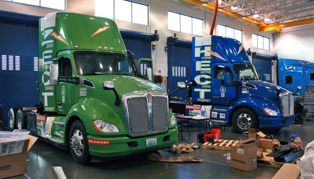 Paccar Kenworth zero-emission electric and hybrid transport semi-trucks with custom green and blue large format vinyl fleet wraps.