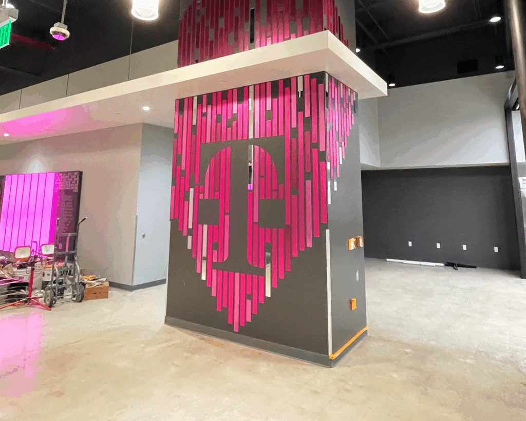 Photo of T-Mobile printed acrylic installation, produced and installed by SuperGraphics. Showcases column covered in laser-cut acrylic pieces to assemble a T-Digit at T-Mobile Call Center.