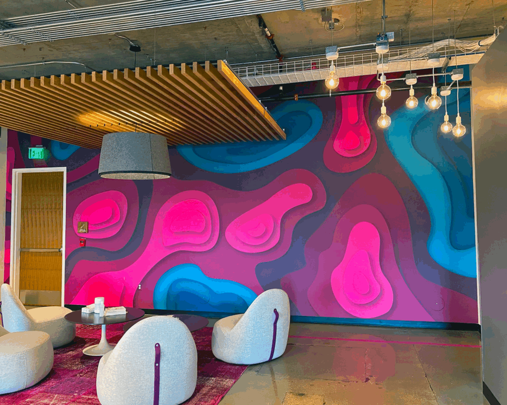 Large, colorful die-cut vinyl wall mural in a corporate lobby featuring vibrant magenta, cyan, and blue layered organic shapes.
