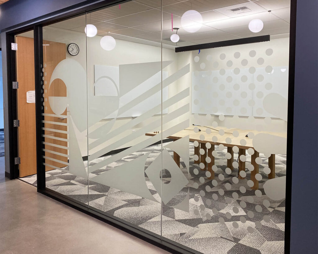 Frosted glass conference room graphics featuring abstract shapes, stripes, and dotted patterns in a modern office setting.