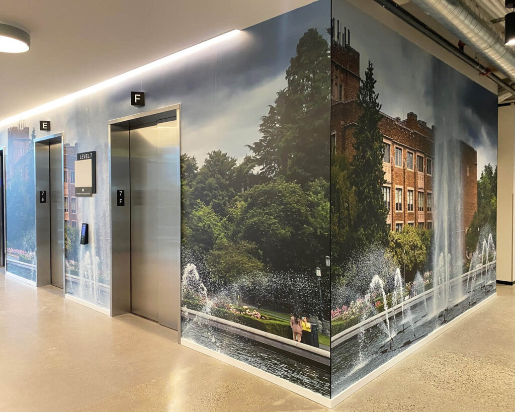 University of Washington elevator bay wrapped in large-scale wall graphics featuring Drumheller Fountain and campus scenery.