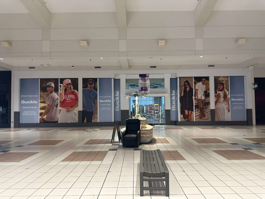 Wide mall storefront featuring Buckle barricade graphics with large lifestyle photography panels and “Style Your Way — Coming Soon!” branding, produced and installed by SuperGraphics.