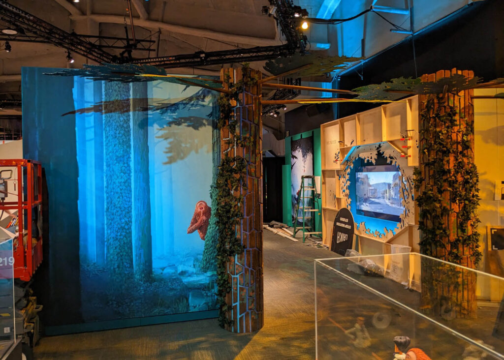 Immersive forest-themed environment from MoPOP’s Hidden Worlds: The Films of LAIKA exhibit, featuring large-format environmental graphics, dimensional columns, and integrated media, produced and installed by SuperGraphics.