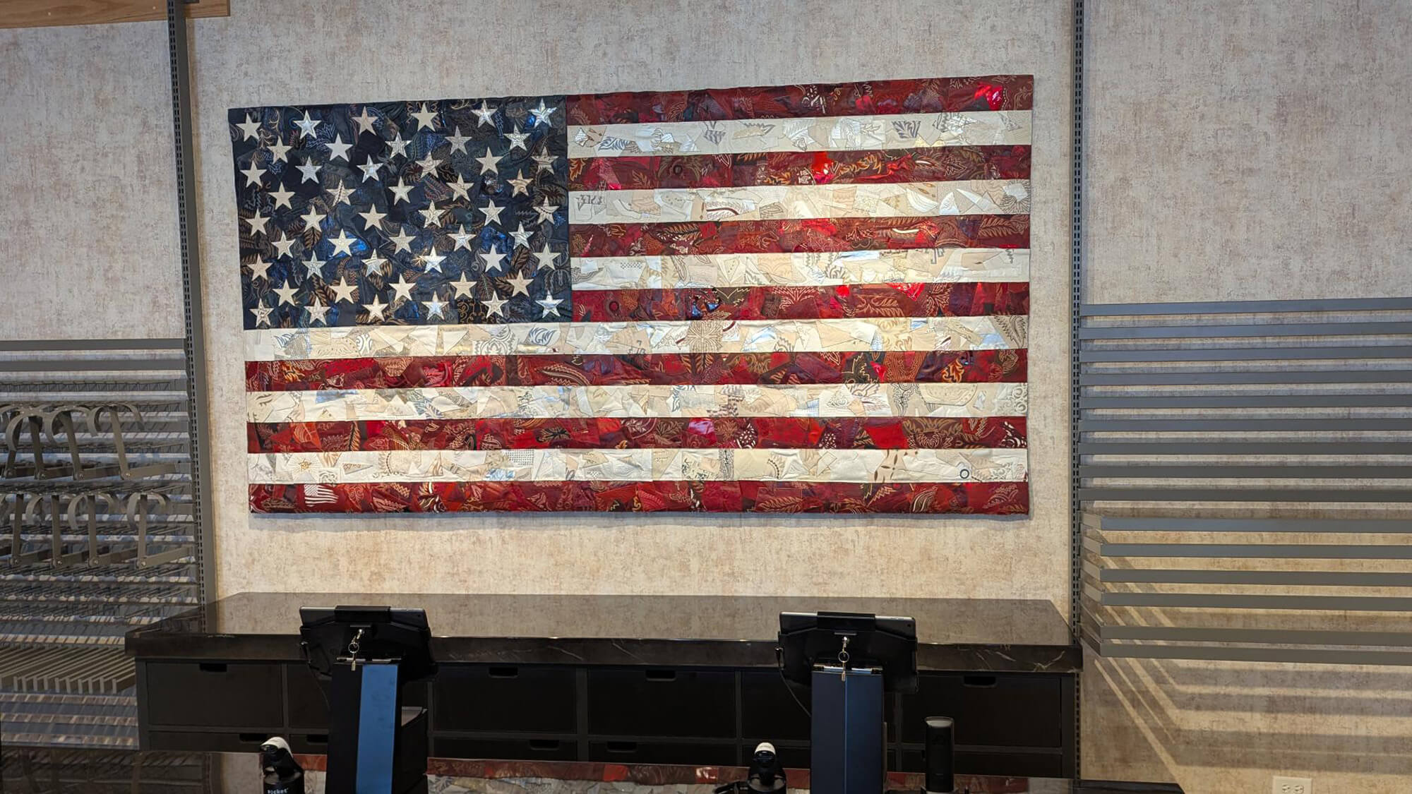 Custom American flag wall art installed inside Ariat International, displayed above a retail checkout counter with textured layered materials and metallic detailing.