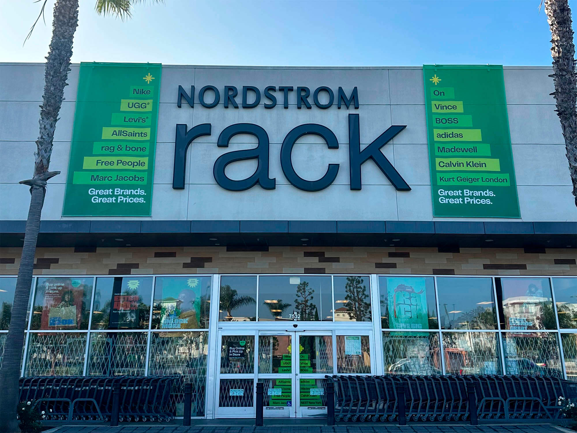 Nordstrom Rack storefront featuring large green promotional banners mounted on the building facade, produced by The Imagine Shop by SuperGraphics for the 2025 Holiday campaign.