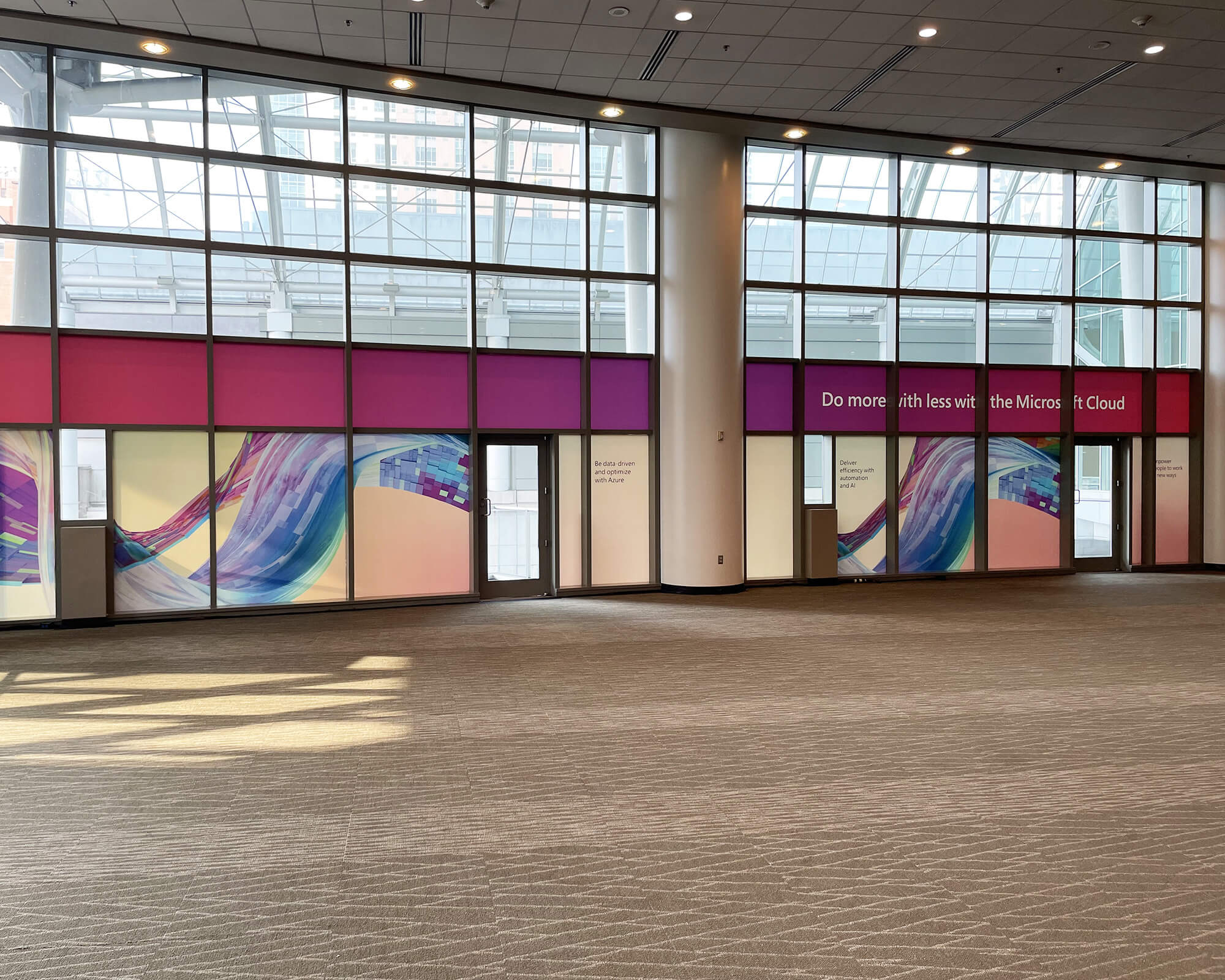 Sustainable large-format branded window graphics produced and installed by SuperGraphics for Microsoft Ignite, featuring colorful abstract designs across a convention center glass facade.