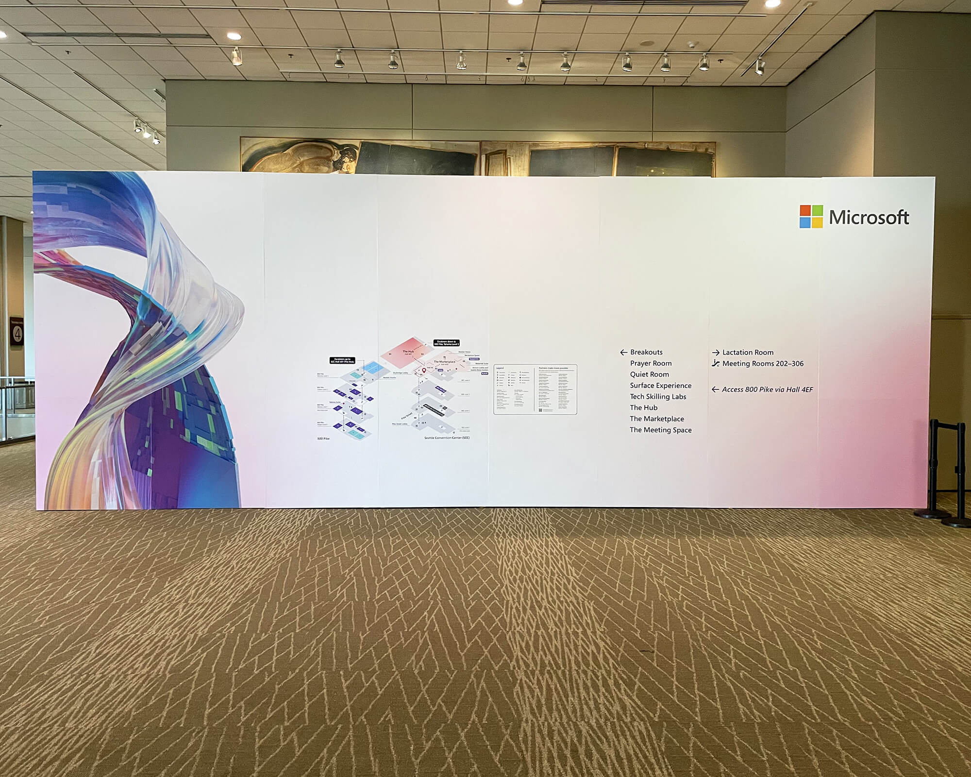 Sustainable large-format freestanding wayfinding wall produced and installed by SuperGraphics for Microsoft Ignite, featuring a venue map, directory, and colorful abstract branding.