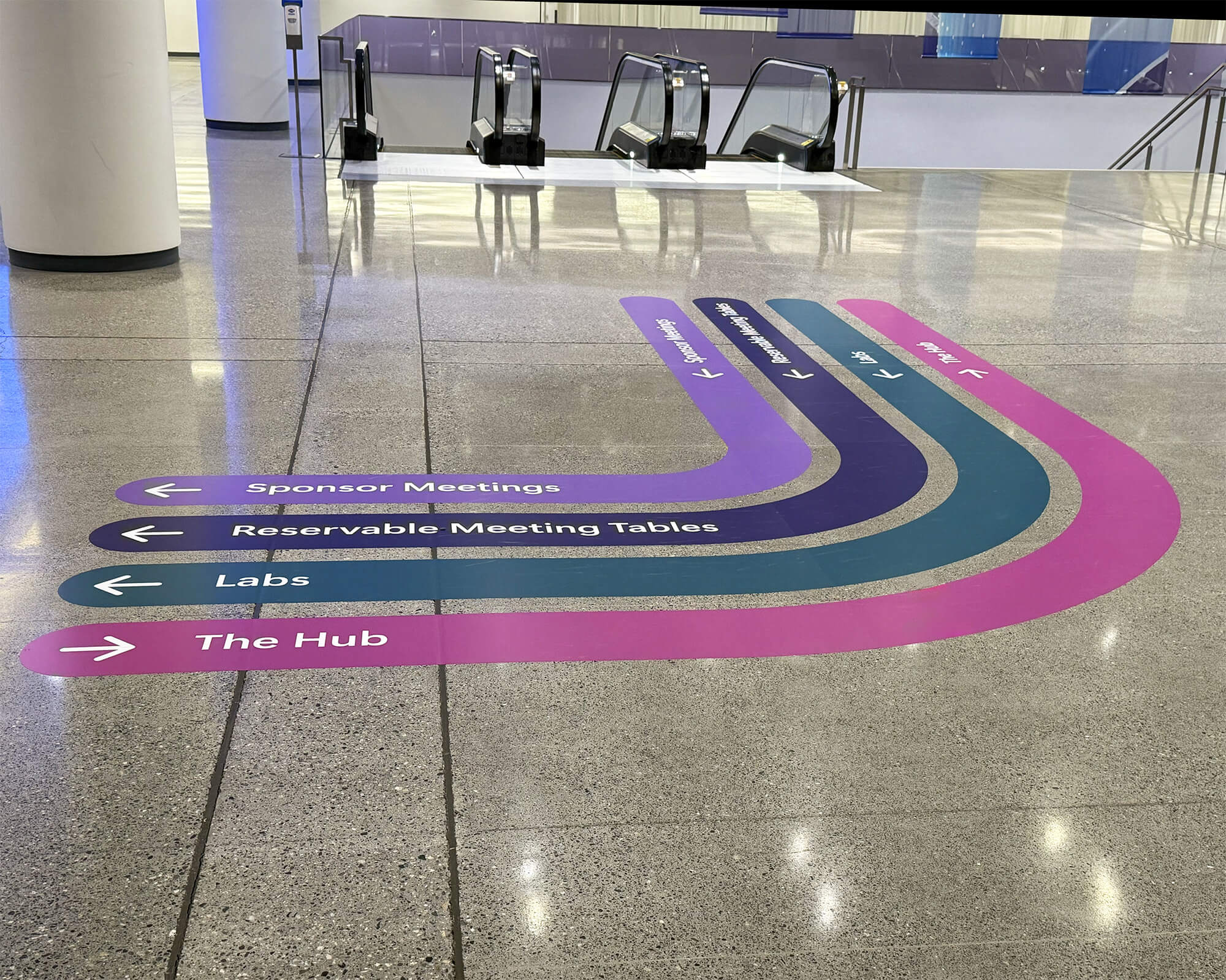 Sustainable color-coded floor wayfinding graphics produced and installed by SuperGraphics for Microsoft Ignite, with directional paths guiding attendees to The Hub, Labs, Reservable Meeting Tables, and Sponsor Meetings.