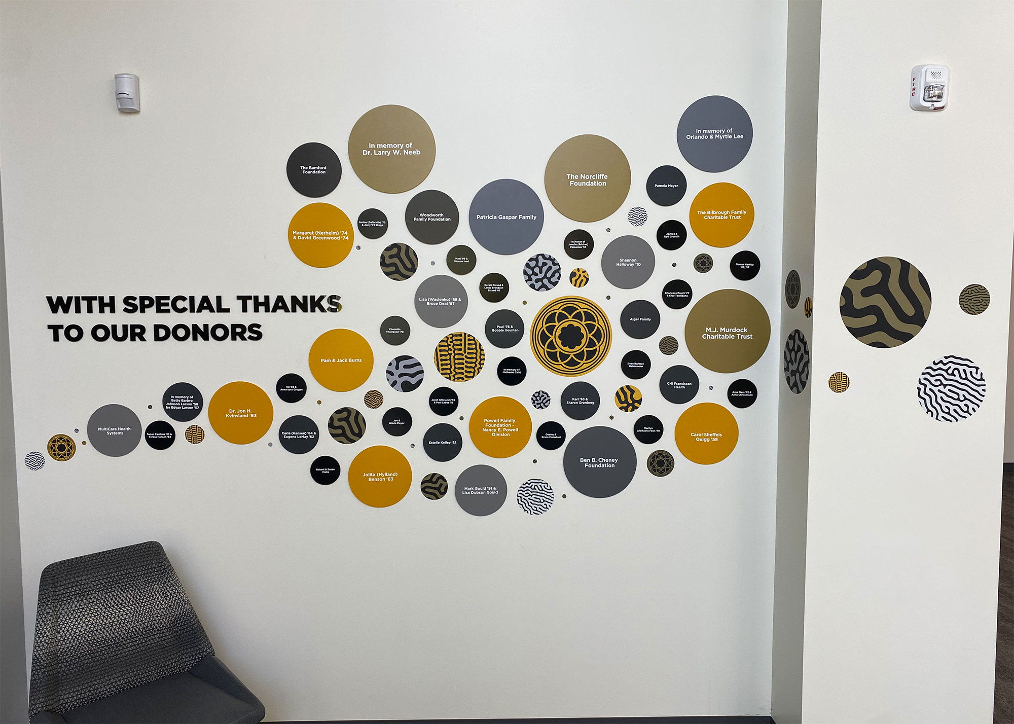 PLU donor recognition wall featuring a dynamic arrangement of dimensional circles in gold, black, and grey with donor names, produced by SuperGraphics.