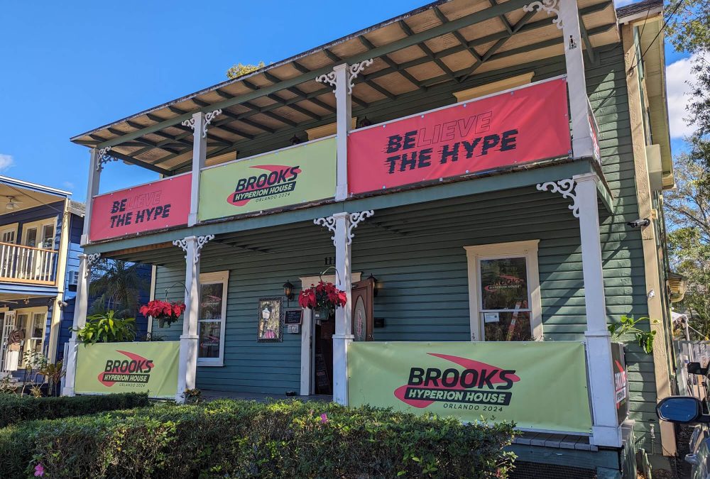 Building banners installed on outside of house for Brook's Hyperion House pop-up event. Showcases bold pink and yellow banners attracting marathon runners to the building.