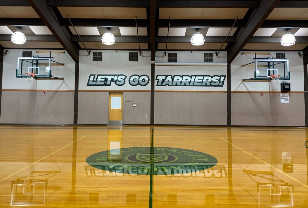 Charles Wright Academy gym graphics, produced and installed by SuperGraphics. Showcases messaging "Let's go Tarriers" on wall.