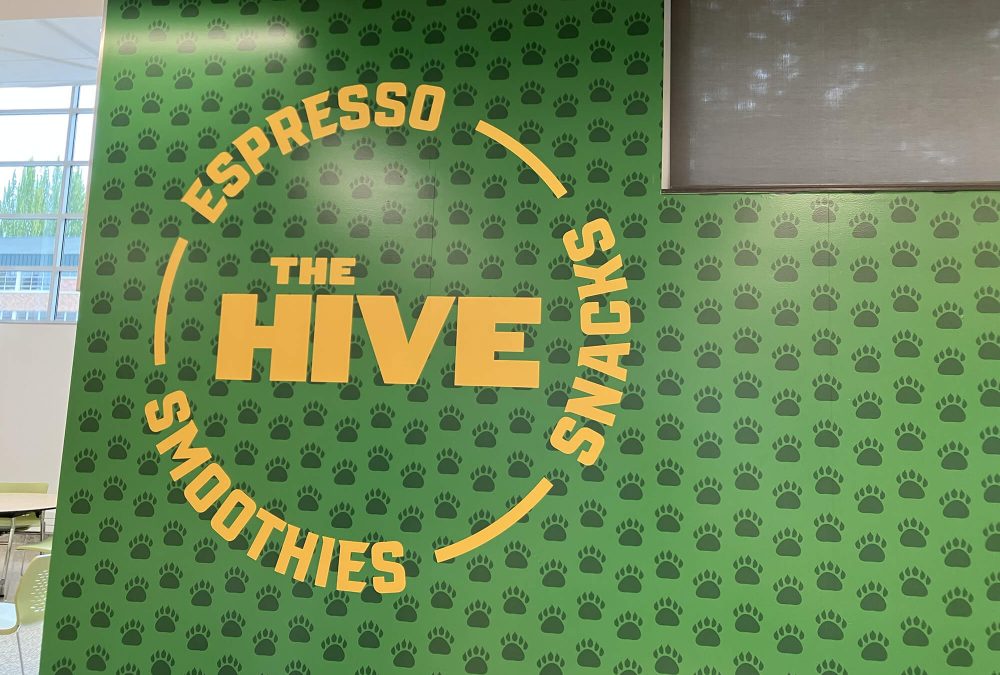 Charles Wright Academy Wall Graphics, produced and installed by SuperGraphics. Showcases logo for The Hive, a student store, on top of green bear paw iconography.
