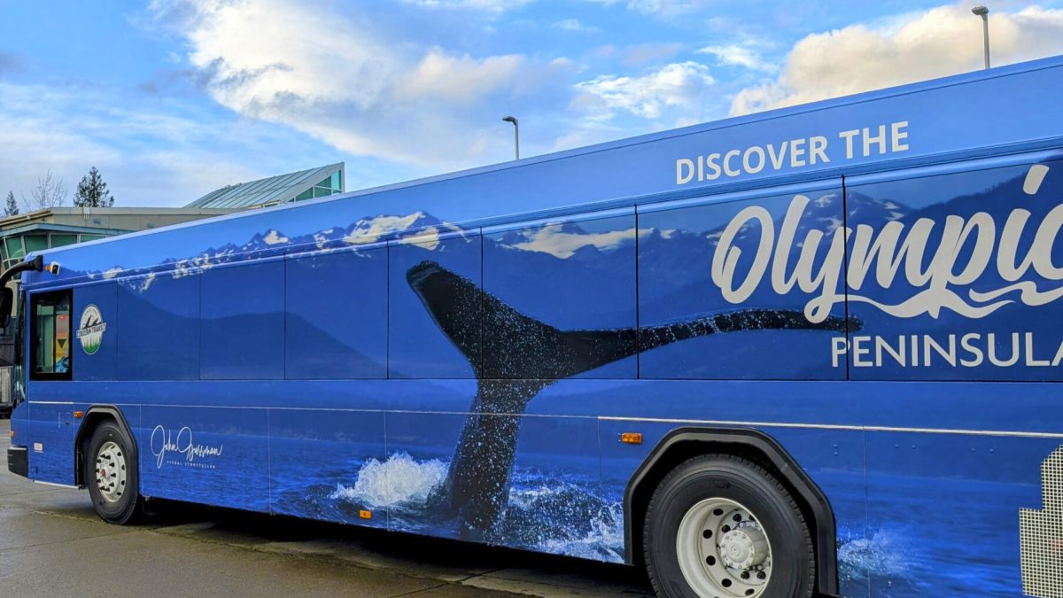 A Clallam Transit bus wrapped in a visually stunning design showcasing the Olympic Peninsula. The full-color graphic highlights the region's natural beauty and diverse landscapes, emphasizing outdoor recreation and tourism