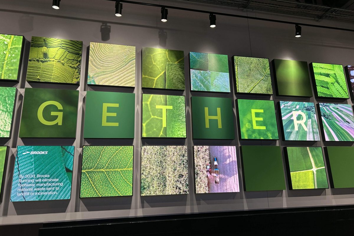 Grid-style environmental graphic installation at Climate Pledge Arena featuring green-toned imagery, textured patterns, and typographic panels spelling a sustainability message, produced and installed by SuperGraphics.