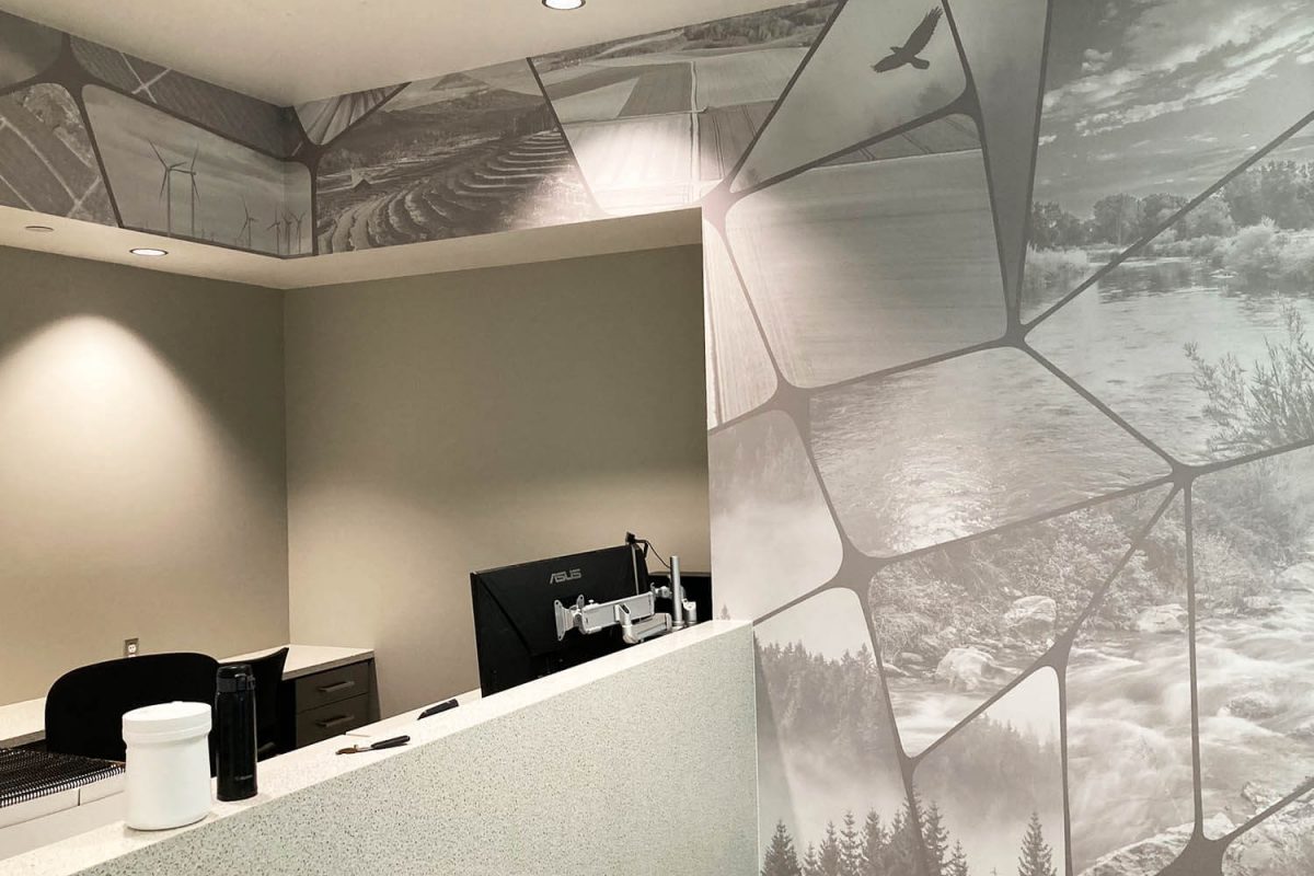 Black-and-white environmental wall mural featuring segmented landscape photography installed behind a corporate reception desk.