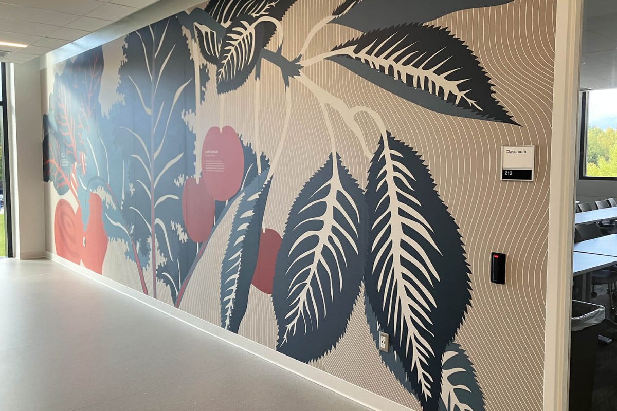 Large botanical wall mural featuring stylized leaves and plants in muted blue, coral, and beige tones along a bright hallway.