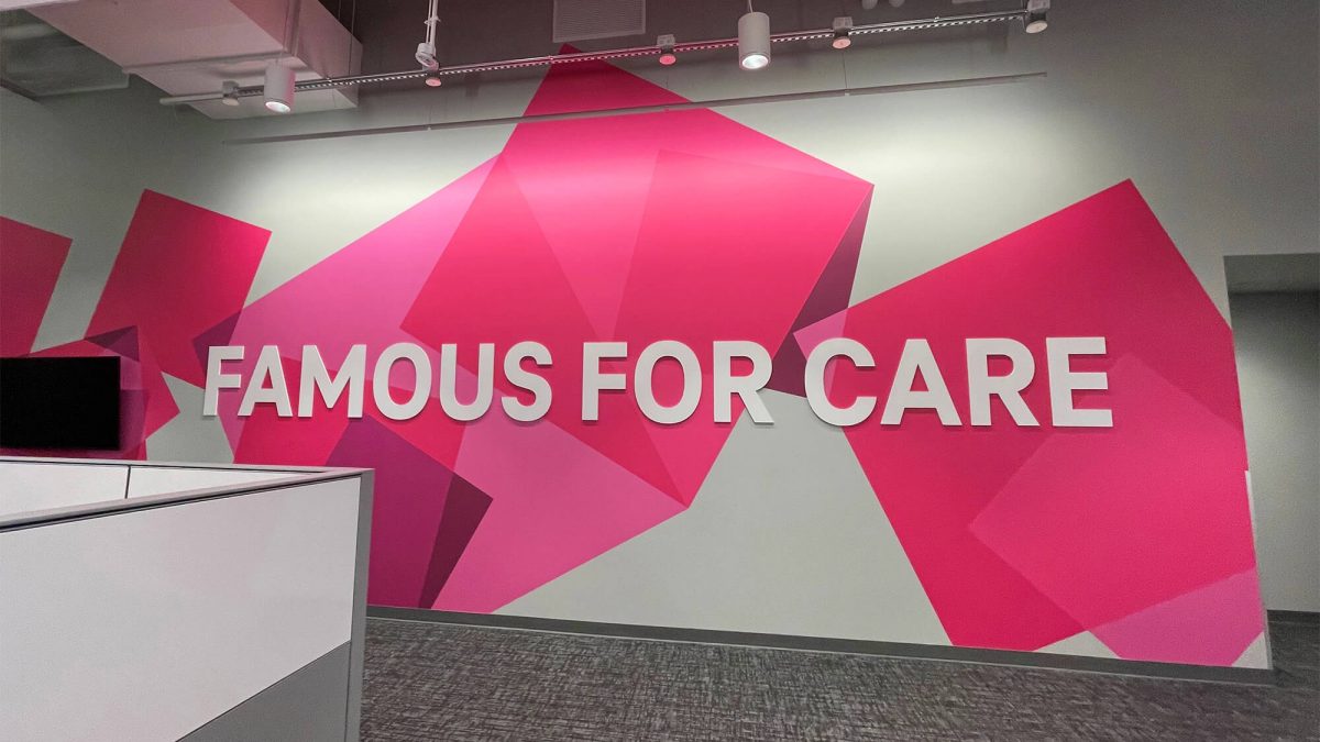 Corporate office wall graphic, produced and installed by SuperGraphics. Showcases T-Mobile's pink branding rotating cubes design with the message, "Famous for care."