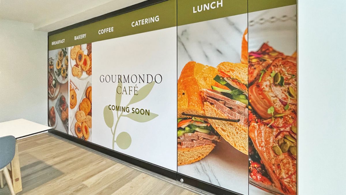 Indoor promotional graphics for Gourmondo Café's new location in Seattle.