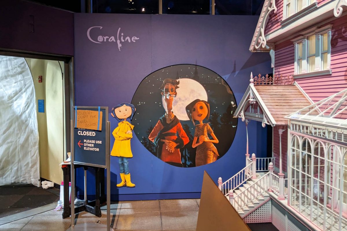 Exhibit scene from MoPOP’s Hidden Worlds: The Films of LAIKA featuring Coraline character graphics, a moonlit wall illustration, and a dimensional house façade, produced and installed by SuperGraphics.
