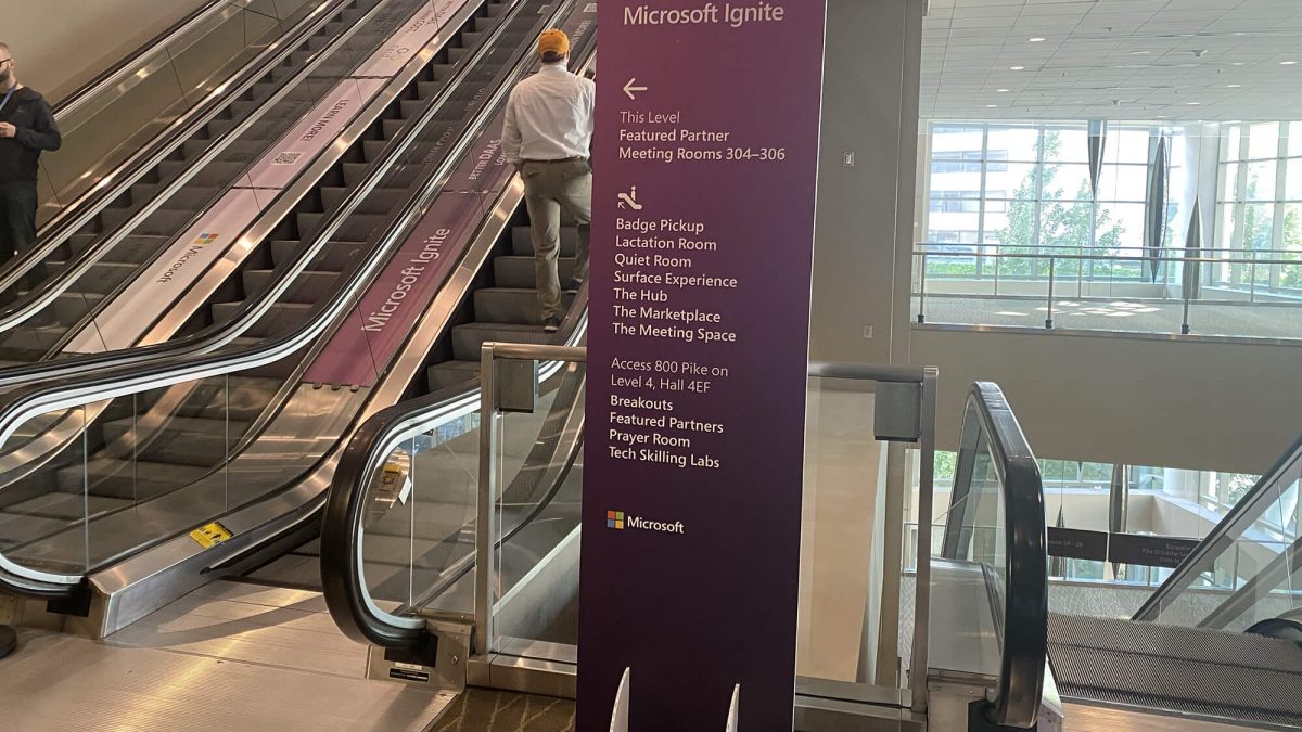 Microsoft event wayfinding signage, produced and installed by SuperGraphics. Shows purple freestanding signage with directional signage next to escalator.