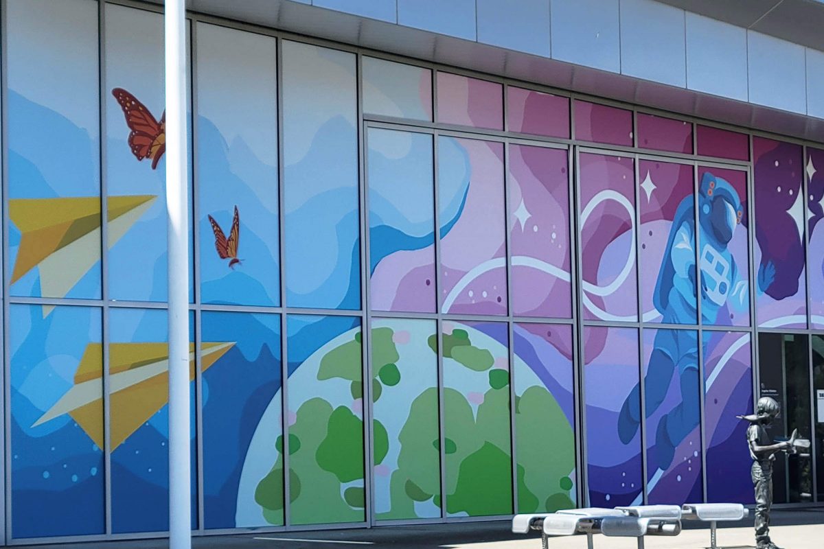 Exterior window graphics at The Museum of Flight featuring colorful illustrated space and aviation imagery applied across a glass façade, produced and installed by SuperGraphics.