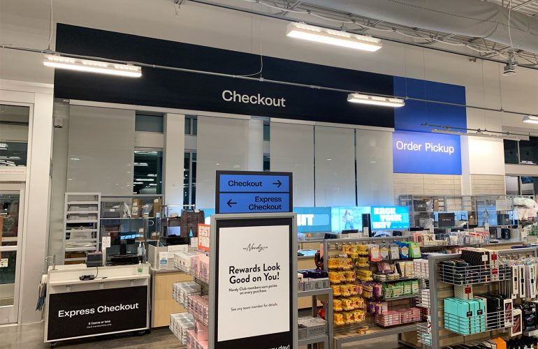 Nordstrom Rack rebrand campaign. Showcases black wall graphics stating Checkout, and Blue wall graphics stating Order Pickup. There is additional rebranded signage on the floor.