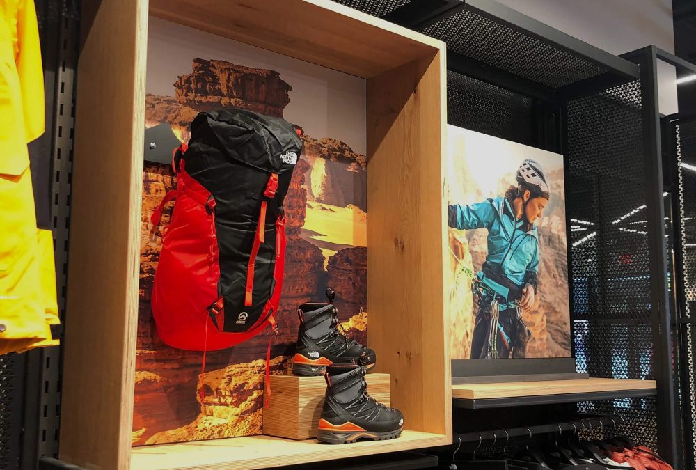 Custom fabric display inserts featuring desert rock climbing imagery inside The North Face retail shadowbox merchandising units produced by SuperGraphics