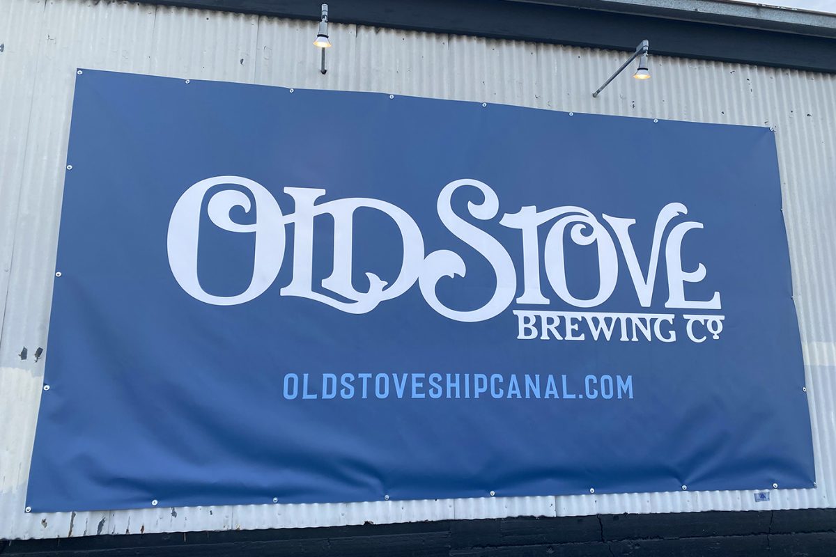 Old Stove building banner, produced and installed by SuperGraphics. Showcases old stove logo and contact information.