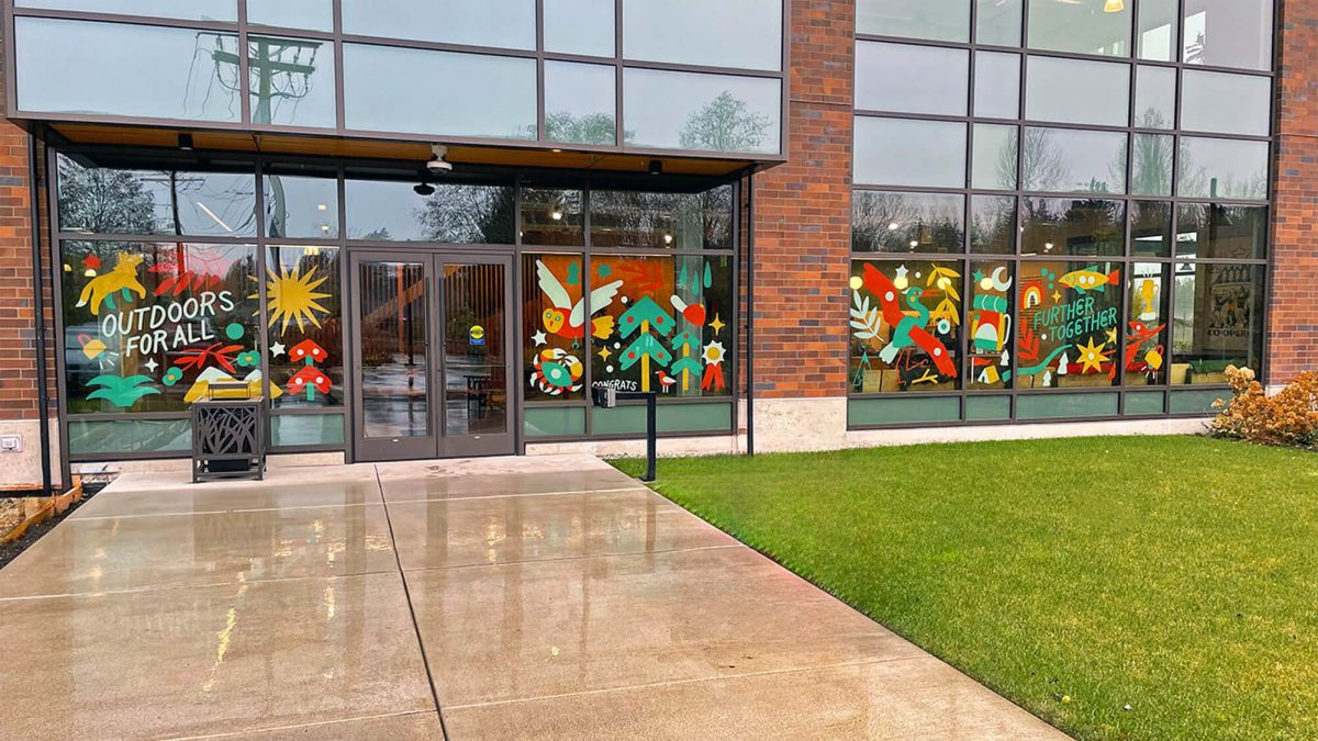 Window graphics for REI store, produced and installed by SuperGraphics. Features outdoor graphic illustrations with text 'Outdoors for all' and 'Further Together;