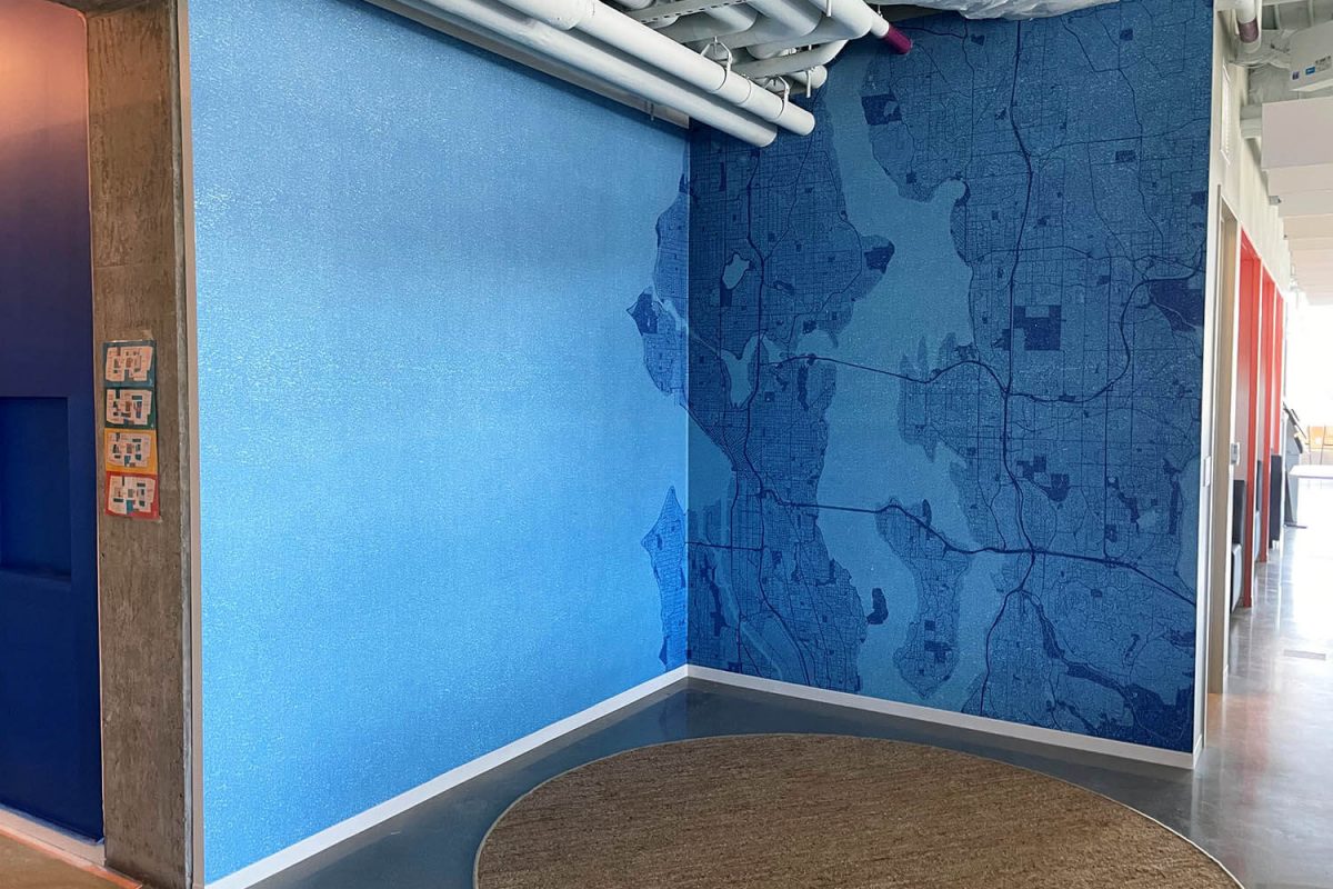 Wall mural featuring a monochromatic blue map of the Seattle area transitioning into a textured blue gradient on the adjacent wall.