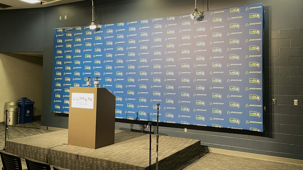 Seattle Seahawks backdrop banner, produced and installed by SuperGraphics. Showcases step-and-repeat Seahawks logos in front of press conference podium.
