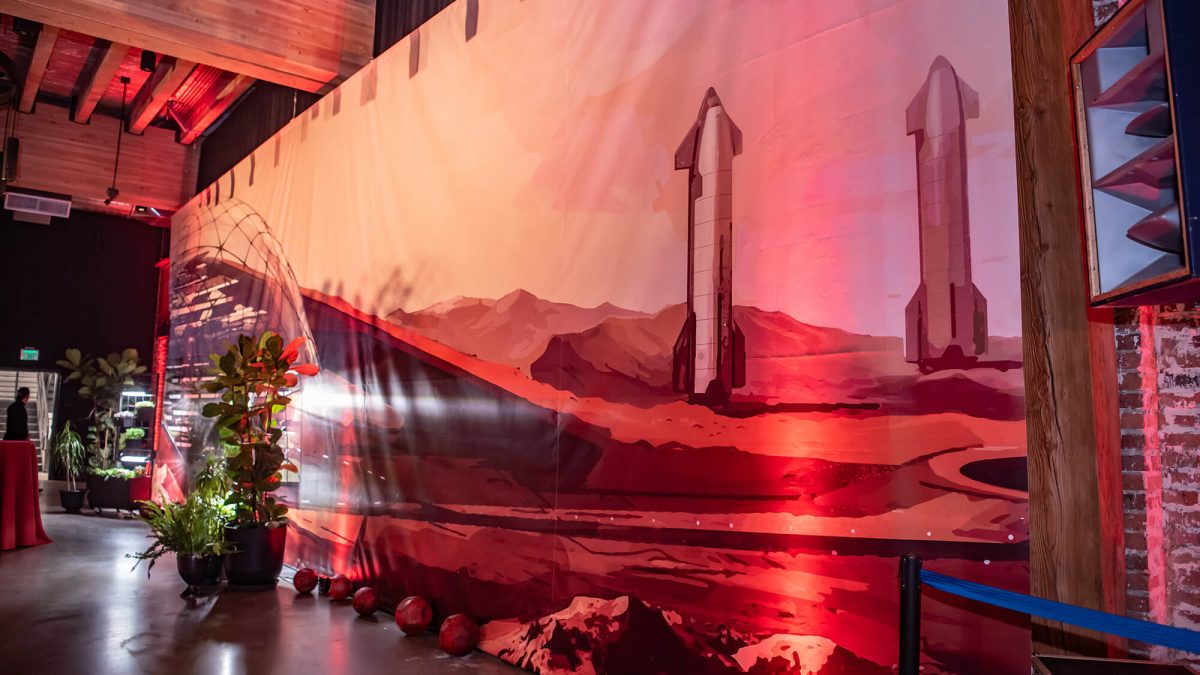 SpaceX Event banner, produced and installed by SuperGraphics. Photo taken by Jean Marcus Strole. Event banner spans from floor to ceiling, showcasing SpaceX rockets on mars.