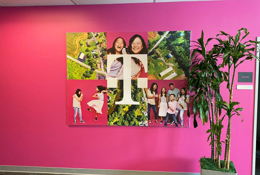 Custom SEG fabric frame featuring T-Mobile logo with community and family lifestyle imagery on a magenta wall in a corporate office produced by SuperGraphics