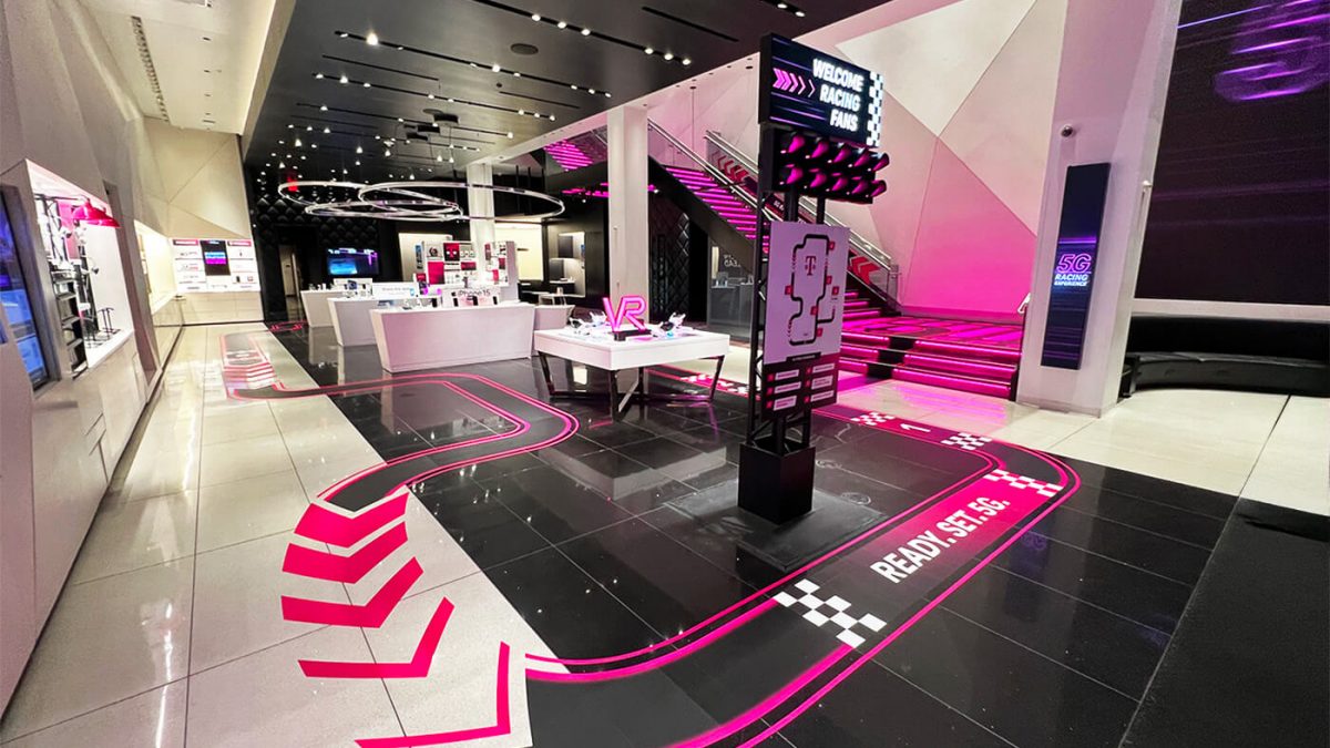 Store graphics for T-Mobile and F1 collaboration within T-Mobile flagship store. Shows pink racing floor graphics to guide customers through the store.