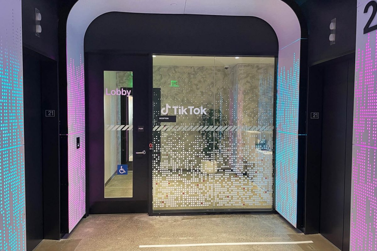 TikTok office entrance with gradient wall graphics and custom dotted privacy film on glass doors.