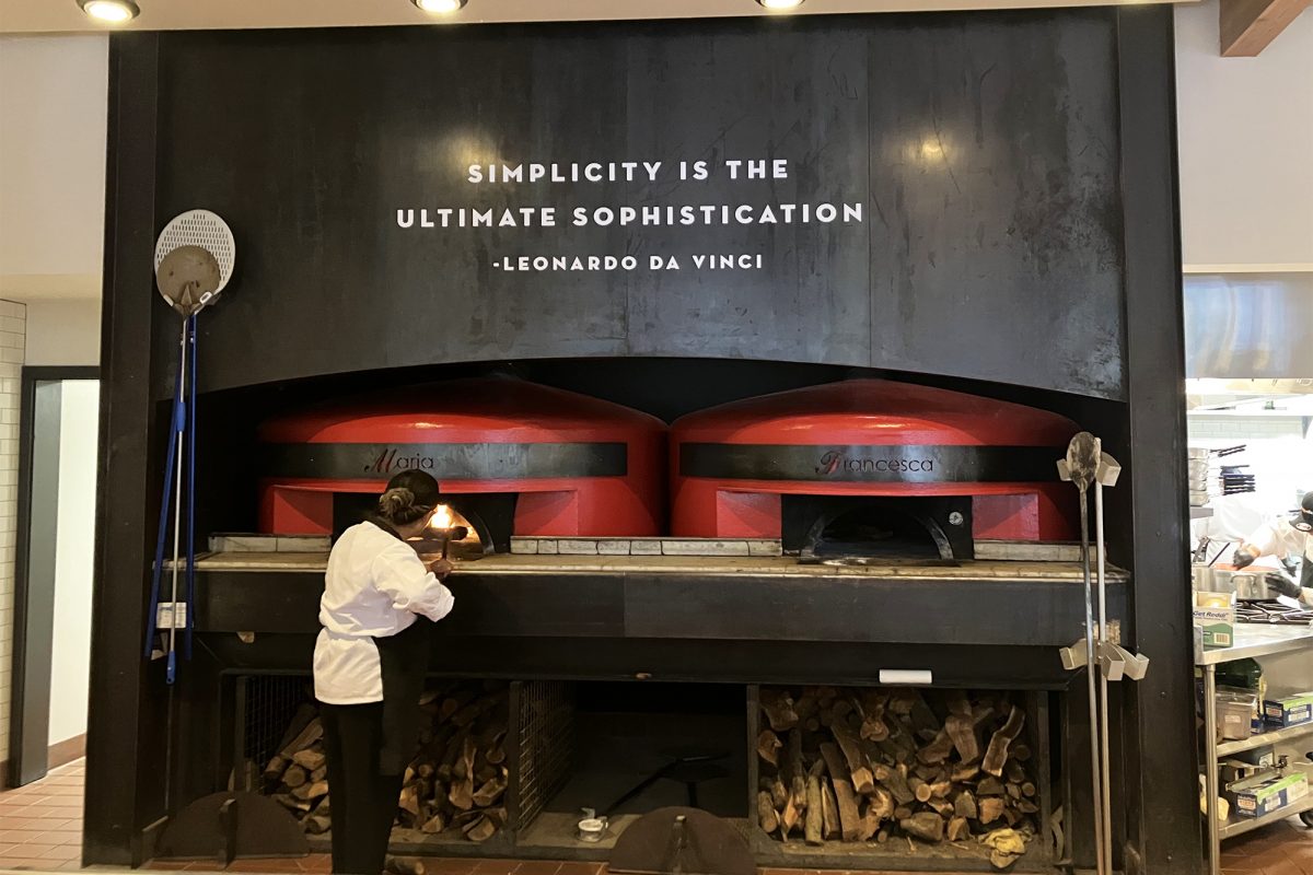 Tutta Bella dimensional lettering, produced and installed by SuperGraphics. White dimensional lettering messages inspirational quote above black wood-fire stove.