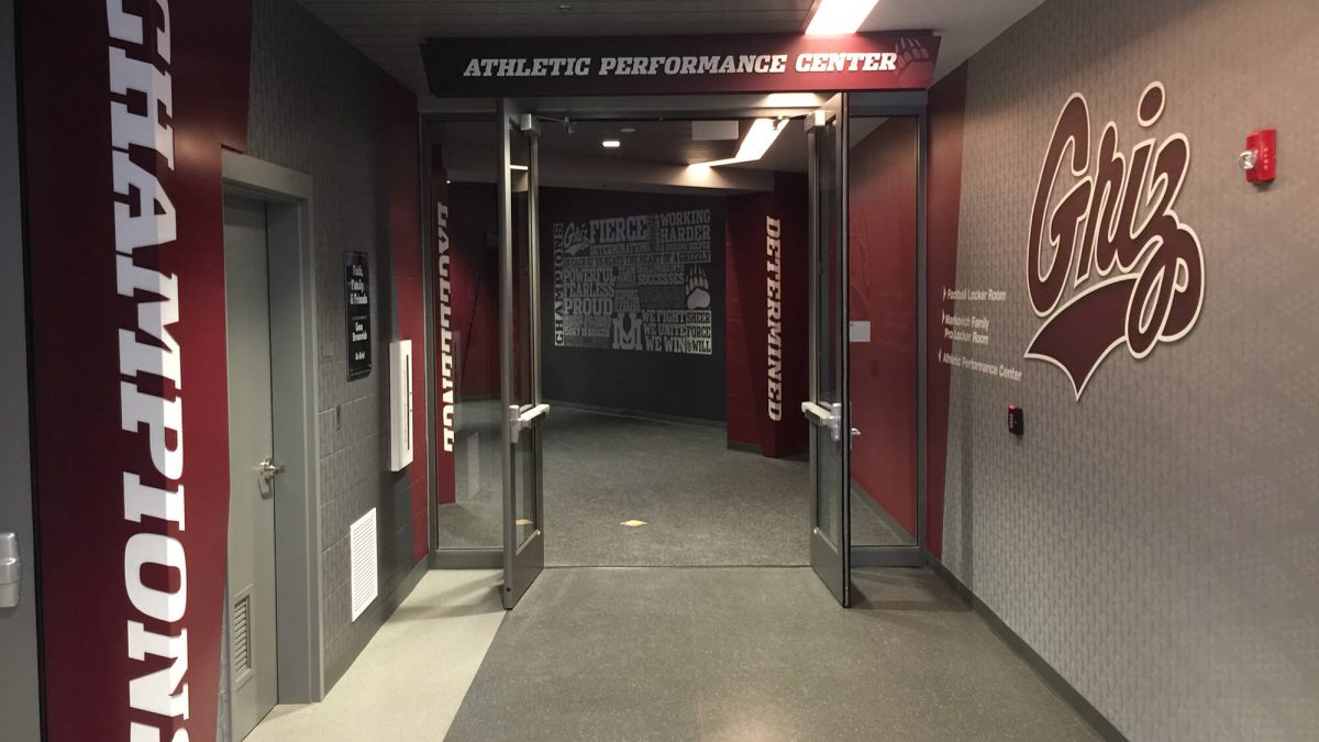 University of Montana Athletics Facility branding, produced and installed by SuperGraphics. Showcases UM athletics messaging and logos extending down hallway.