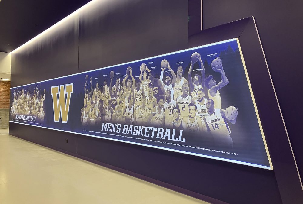 Large backlit SEG fabric frame celebrating University of Washington Men's Basketball history installed in an athletic facility produced by SuperGraphics