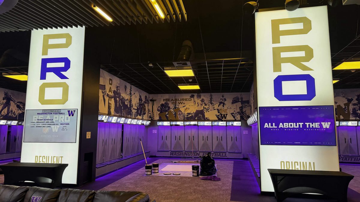 University of Washington Football locker room signage, produced and installed by SuperGraphics. Features backlit graphics saying "Pro", along with wall murals behind player lockers.